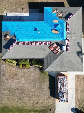 Roof replacement crew removing storm tarp and starting dry-in