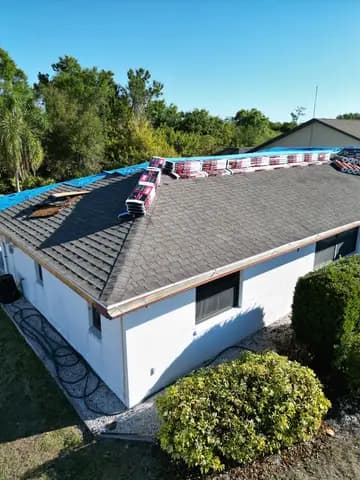 Roofing crew installing new shingles with bundles staged on the roof