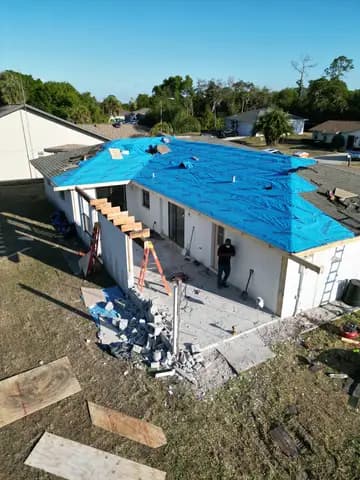 Storm-damaged roof under tarp before replacement — roofing project by Vertical Builders and Commercial