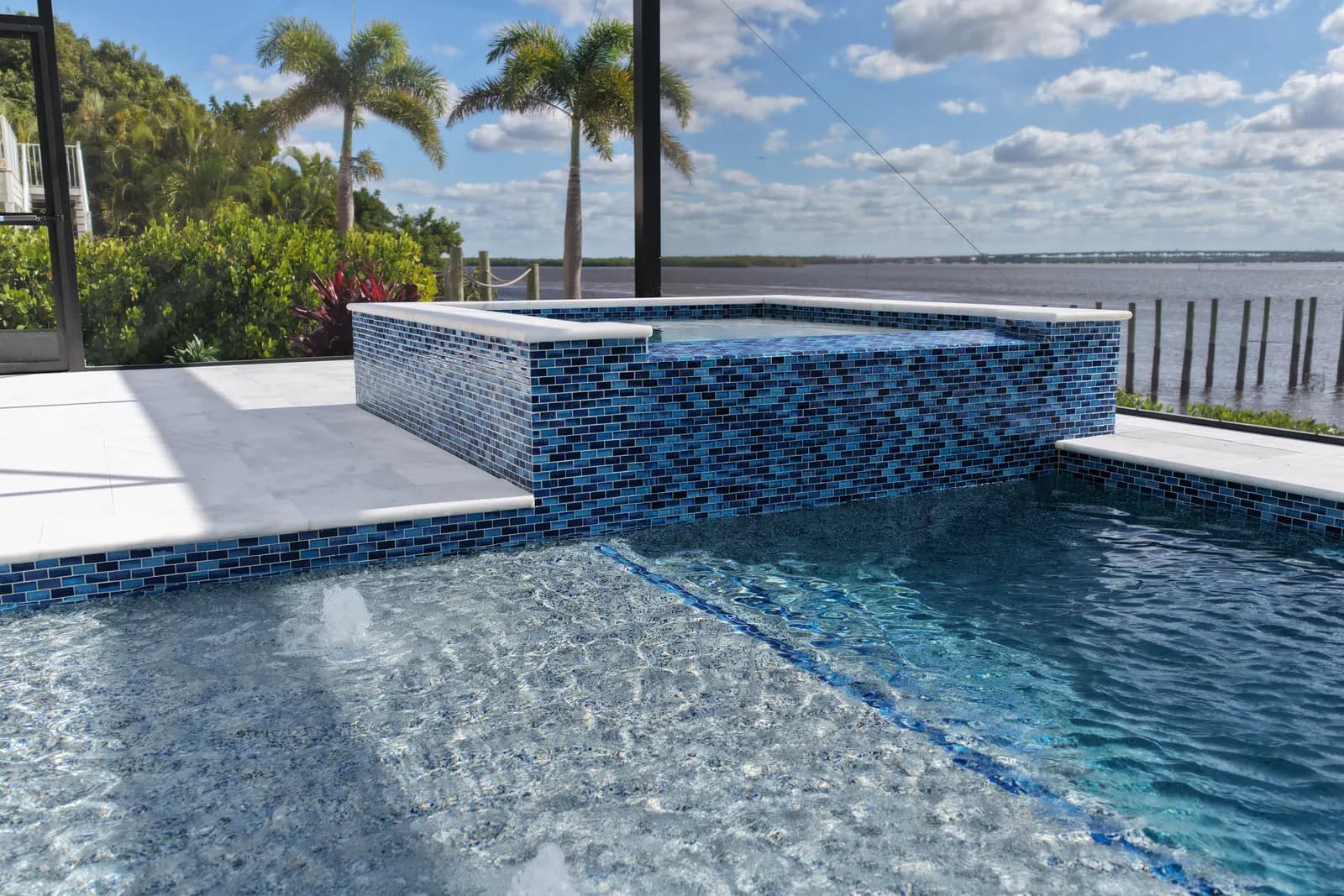 Finished waterfront pool and spa with blue mosaic tile